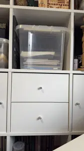 Clear lidded box of drawing paper pads in a cube shelf cubby above the drawing table