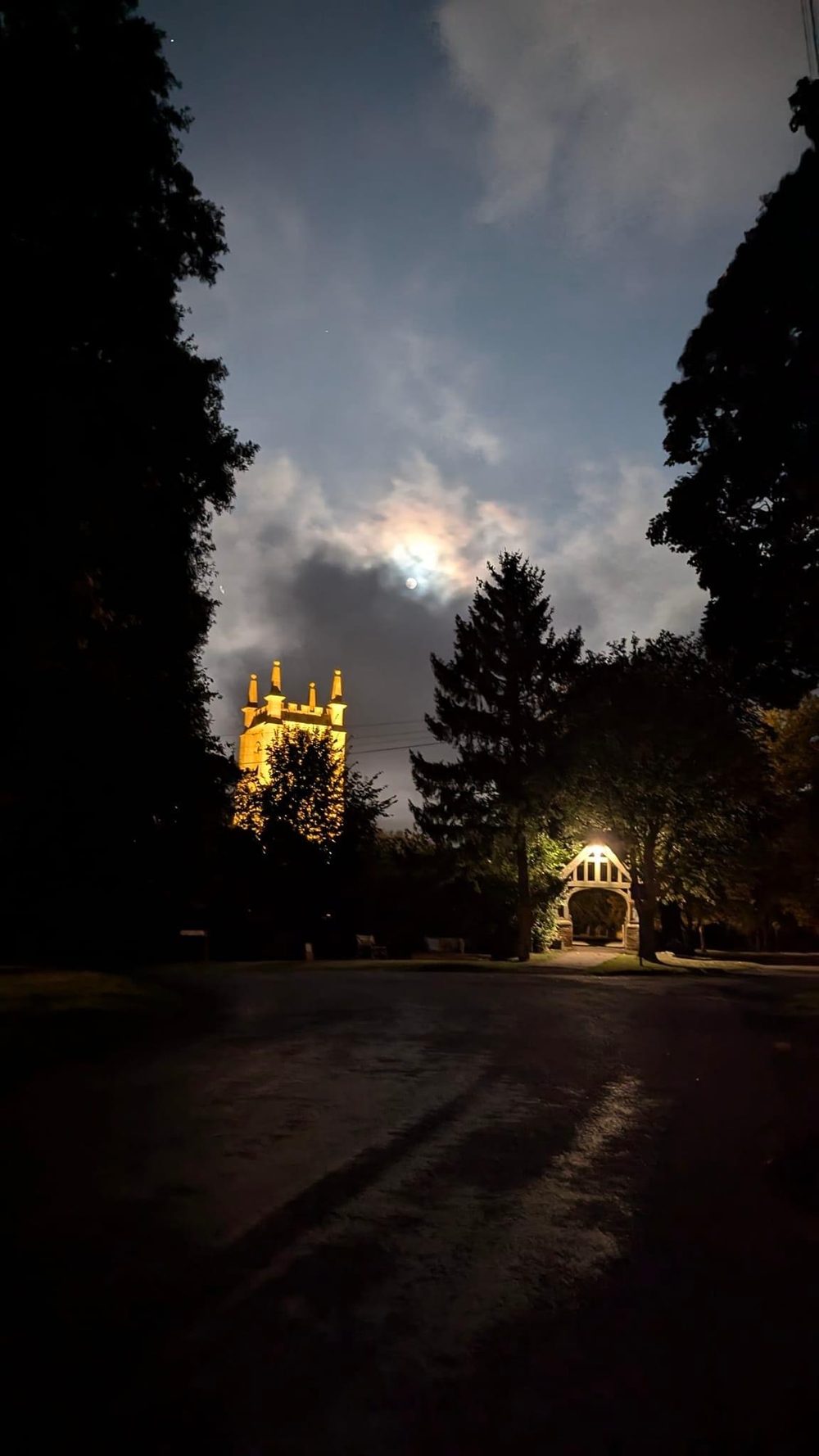 Floodlit church tower glowing against a dark moonlit sky