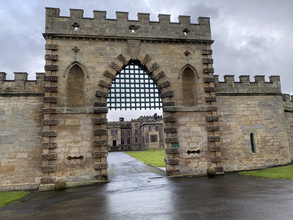 Crenellated stone gatehouse with a portcullis and rusticated quoins at Ford Castle