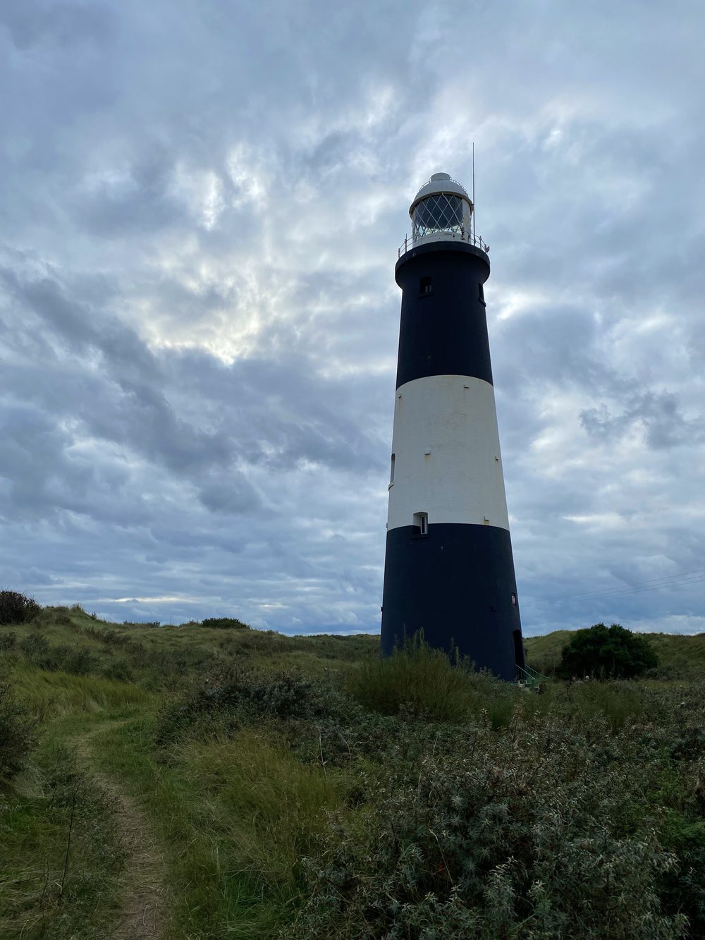 Black and white banded lighthouse standing alone against a dramatic sky