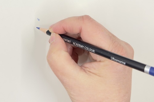 Hand demonstrating holding a coloured pencil near the sharpened tip for precise control and detailed work.