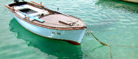 boat in clear turquoise water showing submerged form and reflection