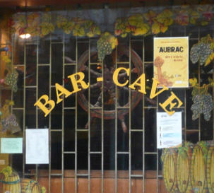 Close up of the shopfront window showing the interior grill and posters