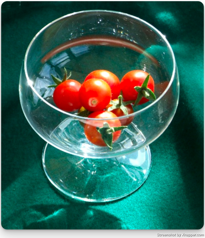Reference photo: cherry tomatoes in a footed glass bowl, lit from one side