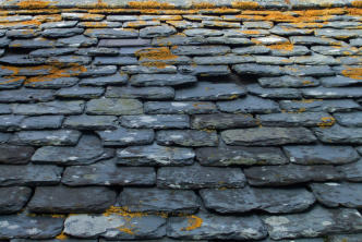 Grey quarried stone roof tiles in uneven rows