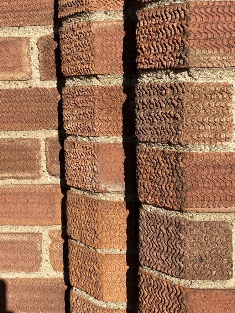 Textured red brick catching low raking sunlight along each brick's top edge