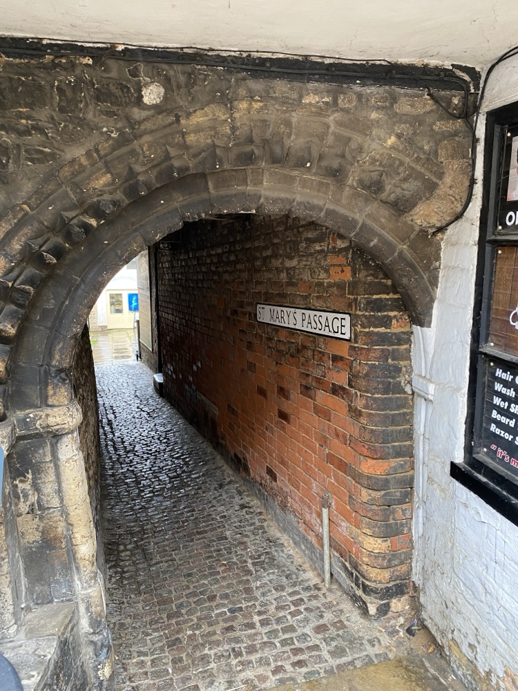 Stone archway with wedge-shaped voussoirs curving over a red brick wall