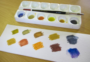 Watercolour pencil wash palette: dry pigment scribbled on rough paper with mixed liquid washes above